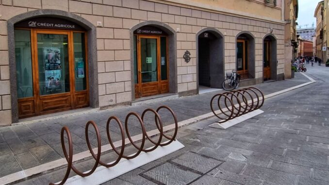 In centro moderne rastrelliere portabici e cestini per raccolta differenziata